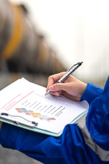 Wall Mural - a worker is checking on chemical hazardous material checklist form with background of train tanker t