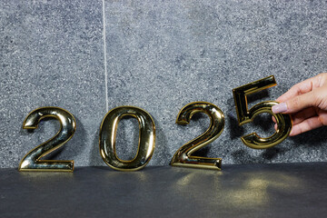 Wall Mural - golden  numbers 2025 two thousand twenty five new year near marble stone and hand hold five 