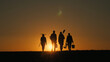 © StockMediaSeller - Against the backdrop of the setting sun, a family of farmers walks across a field, carrying agricultural implements for planting.