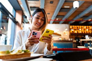 Latin businesswoman managing two phones in a busy café