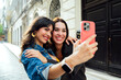 © Miguel Lifestyle - Two pretty friends taking a selfie on the street