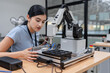 © Nassorn - Hispanic engineer woman working on AI technology in robotics electronics engineering laboratory. University students' research project is programming robot machine with intelligent mechanical control
