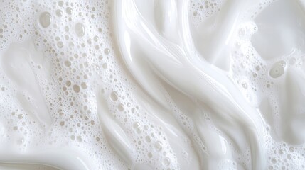 Macro aerial view capturing the dazzling white liquid with air bubbles and a wavy surface. This stunning texture of soap or art cosmetics creates an eye-catching backdrop with ample copy space.