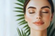 © Jeannaa - Serene woman with closed eyes and natural makeup, surrounded by green plants.