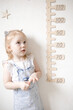 © Victoria - Little girl measuring height with a height meter