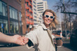 © deagreez - Photo of attractive young cheerful blonde lady hold hand follow pull friend wear trench coat walking outside outdoors