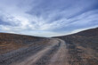 © ABCDstock - Desert gravel road and sky clouds nature background. Road trip in no man's land.