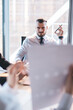 © BullRun - Attentive businessman listening to coworker while sitting and using laptop at meeting in conference room