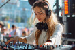 © Michael - Young woman dj playing electronic music at summer outdoor music festival using mixing console and headphones