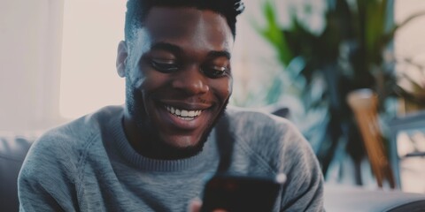 Joyful man texting at home, enjoying social media and browsing the internet. Engaging with mobile apps for shopping and messaging while smiling