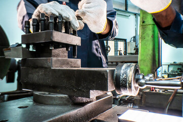 Two focused industrial technicians work together operating heavy machinery in a workshop. The image of teamwork, precision, and technical expertise in an engineering and manufacturing industry