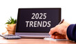 © Dzmitry - Planning 2025 trends new year symbol. Concept words 2025 Trends on beautiful black tablet. Beautiful white background. Businessman hand. Business 2025 trends new year concept. Copy space.
