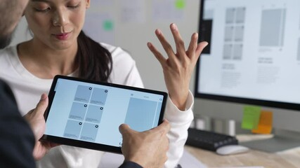 Wall Mural - ux ui designer testing prototype on a tablet, discussing and brainstorming on wireframes for a websi