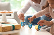 © Pixel-Shot - Happy family celebrating Hanukkah with dreidels at home, closeup