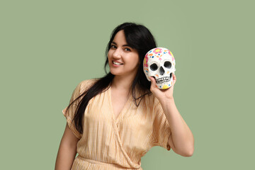 Wall Mural - Beautiful young woman with painted skull on green background. Mexico's Day of the Dead