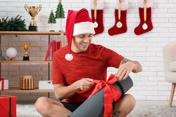 Sticker - Young happy man in Santa hat with new yoga mat in living room decorated for Christmas