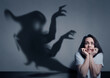 © New Africa - Woman scared by monster. Scary shadow in room