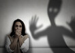 © New Africa - Woman scared by monster. Scary shadow in room