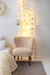 © stock_studio - Cozy Scandinavian white Interior design bedroom with bed and pillows, beige armchair. Decorative wooden ladder with glowing garland and christmas decoration on the white wall background.