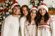 © Iuliia - Family dressed in cozy knit sweaters and Santa hats joyfully celebrating Christmas together