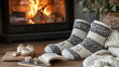 © CHPhotos - A close-up of woolen socks by a fireplace, with a knit blanket and a book nearby, creating a warm and inviting winter scene indoors.