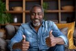 © 怡如 柯 - Happy middle aged black man showing thumbs up on couch in cozy living room