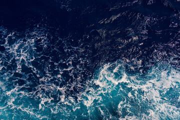 aerial shot capturing the contrast between dark ocean waves and bright white seafoam, creating dynam