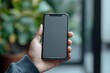 © virza - A Hand Holding a Modern Smartphone with a Blank Screen