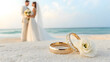 © Pangsiri - Two golden wedding rings with couple in background on beach