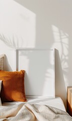 Poster - A cozy indoor scene featuring a blank white frame on a stylish bed with textured pillows and soft throws, illuminated by gentle sunlight and shadow play from nearby plants.
