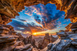 © Butsarakham - A stunning sunset viewed through rocky formations, showcasing vibrant colors and dramatic clouds in a breathtaking natural landscape.