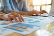 © LadiesWin - Close-up view of hands analyzing charts and documents during a business meeting, focusing on the meticulous process of data analysis