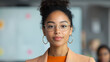 © TH_Stock - Confident young professional woman in office attire, wearing glasses and smiling, stands in a modern office environment with blurred background.