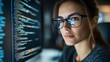 © Maria Mikhaylichenko - Focused female programmer analyzing code on screen, her glasses reflecting the bright display. Cybersecurity expert at work in dimly lit office environment.