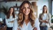 © Larisa AI - A confident woman stands in the foreground, smiling at the camera, with two colleagues in the background, set in a modern office environment showcasing teamwork.