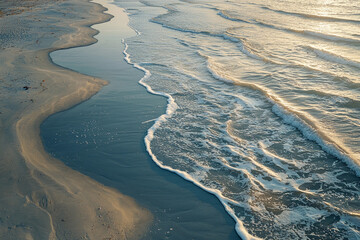 Wall Mural - Gentle waves rolling onto a sandy beach at sunset