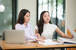 © junjira - Asian business woman working and talking about graph documents