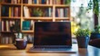 © skdesign - A laptop on a wooden table with black mug and indoor plant with bookshelf at he background