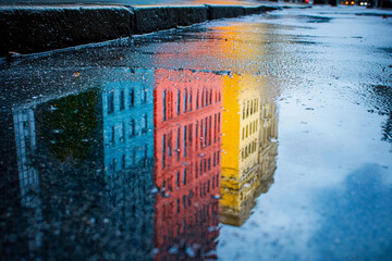 Wall Mural - Colorful reflections in rain puddles on a city street after rainfall