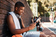 © peopleimages.com - Court, basketball player and man with smartphone for social media, connection and watch video with smile. Sports, male person and athlete with mobile app for fitness tips, advice and scroll outdoor