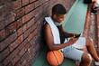 © peopleimages.com - Court, basketball player and man with phone screen for social media, connection and watch video. Sports, happy person and athlete with mobile app for fitness tips, advice and scroll outdoor by above