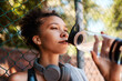 © peopleimages.com - Fitness, woman and drinking water outdoor for health, diet and wellness on break by fence. Sports, bottle and thirsty African athlete with liquid for hydration after exercise, workout and recovery