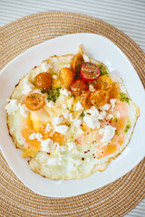 Wall Mural - Fried eggs with marinated cherry tomatoes, herbs and feta cheese