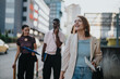 © qunica.com - A group of multicultural business professionals walking together in an urban city environment, exuding confidence and camaraderie. The image captures the essence of teamwork and diversity in a modern