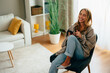 © djile - Woman relaxing at home browsing social media on smartphone and laughing