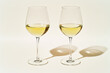 © tatsiana502 - Two glasses of white wine on white background with shadows from sun