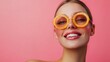 © Juan - Smiling woman wearing orange sunglasses on pink backdrop