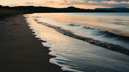 Wall Mural - A quiet beach with soft waves lapping at the shore during sunset.