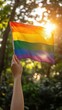 © imagineRbc - A person holding a rainbow flag in a forest. The flag is bright and colorful, and the person is holding it up high. Scene is joyful and celebratory, as the rainbow flag represents the LGBTQ+ community