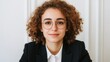 © Tanakorn - Cheerful young businesswoman with curly hair and glasses, smiling confidently